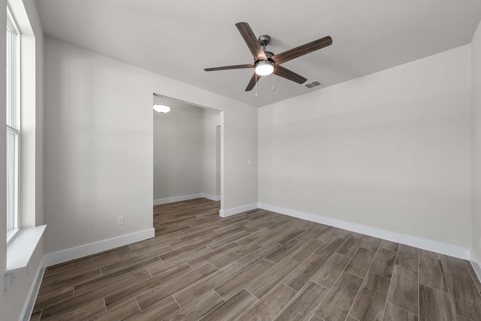 674 Iron Willow Loop Dripping Springs, TX 78620 - Photo 19 of 33 an empty room with wooden floor fan and windows