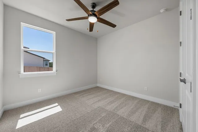 an empty room with a chandelier fan and windows