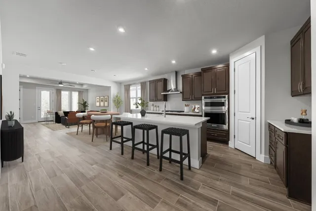 a living room with stainless steel appliances granite countertop furniture wooden floor and a kitchen view