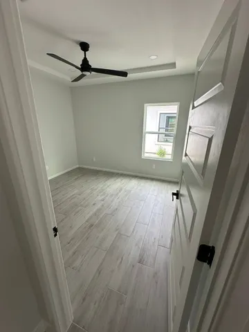 a view of an empty room with wooden floor and a window