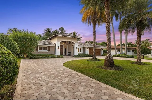 a front view of a house with a garden and tree