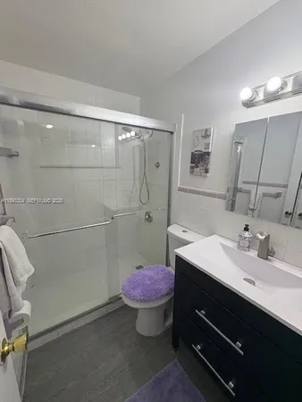 a bathroom with a sink a toilet a mirror and shower