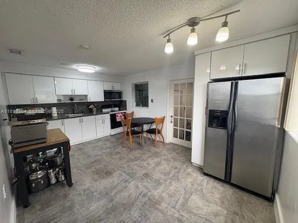 a kitchen with stainless steel appliances granite countertop a refrigerator a stove a sink and a microwave