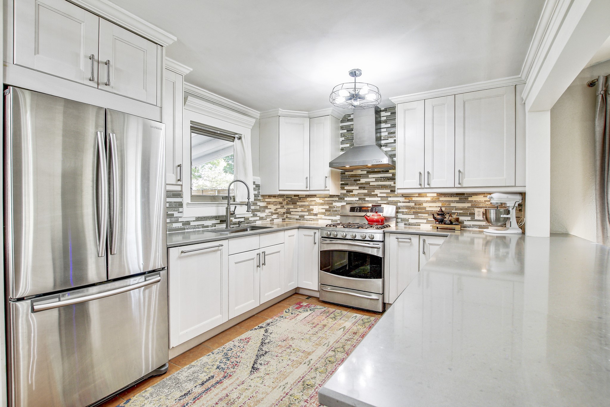 7741 Manassas Drive Austin, TX 78745 - Photo 12 of 39 Kitchen featuring stainless steel appliances, wall chimney exhaust hood, white cabinets, crown molding, and light stone countertops