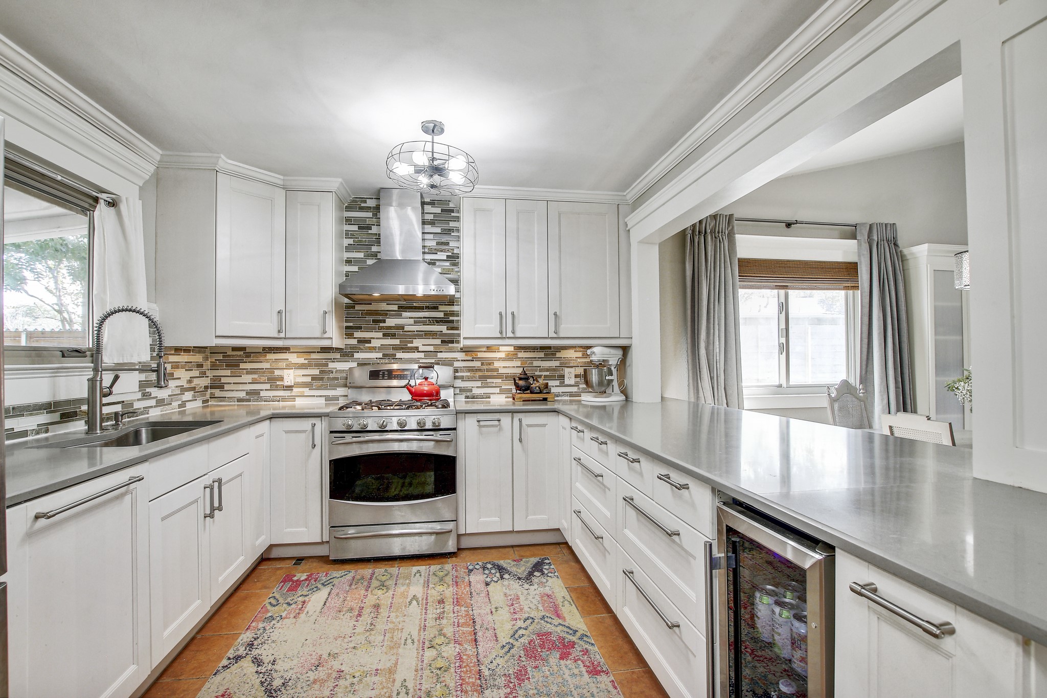 7741 Manassas Drive Austin, TX 78745 - Photo 17 of 39 Kitchen with gas stove, wall chimney exhaust hood, beverage cooler, white cabinetry, and backsplash