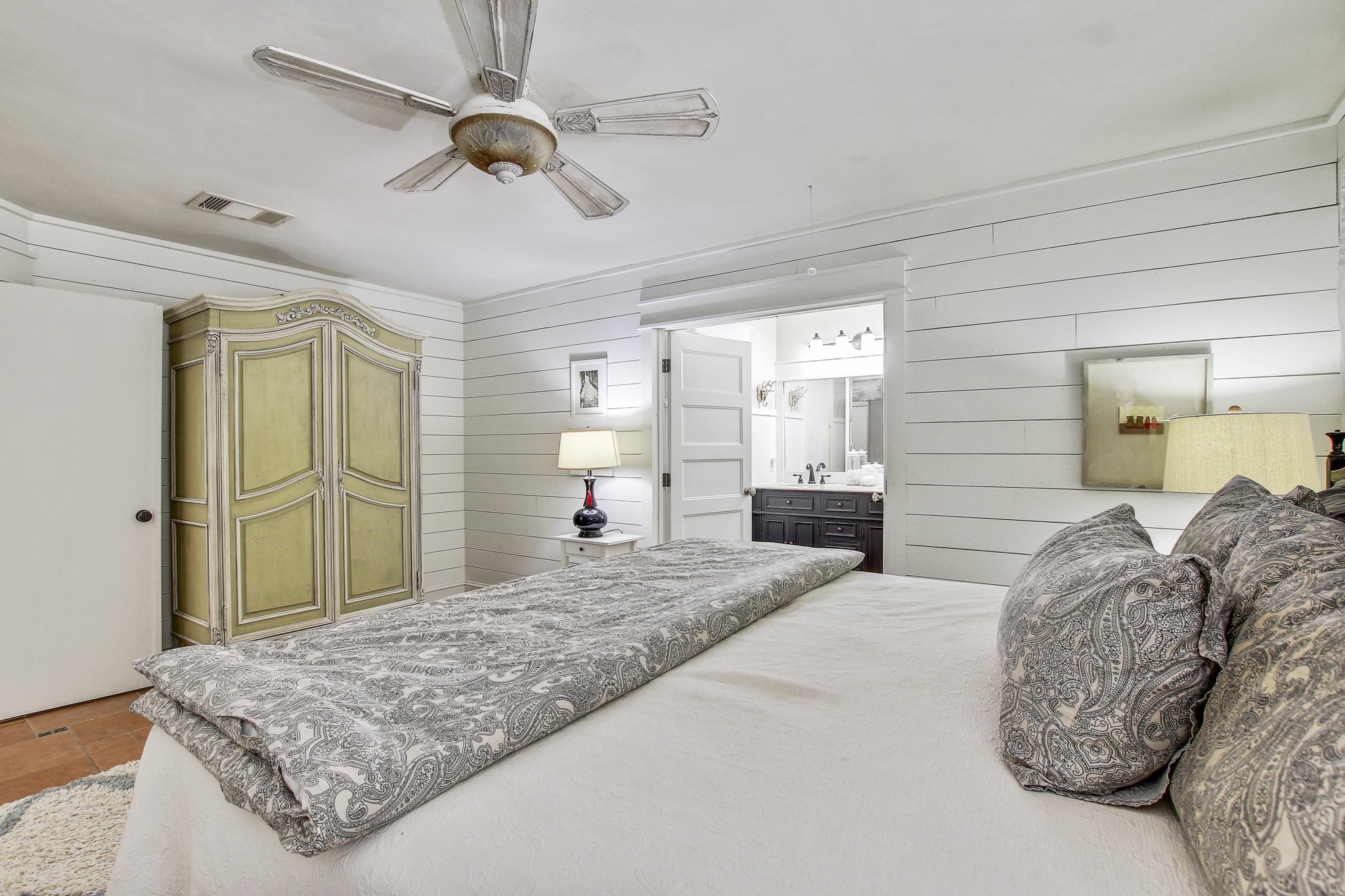 7741 Manassas Drive Austin, TX 78745 - Photo 21 of 39 Bedroom with ensuite bath, wooden walls, and a ceiling fan