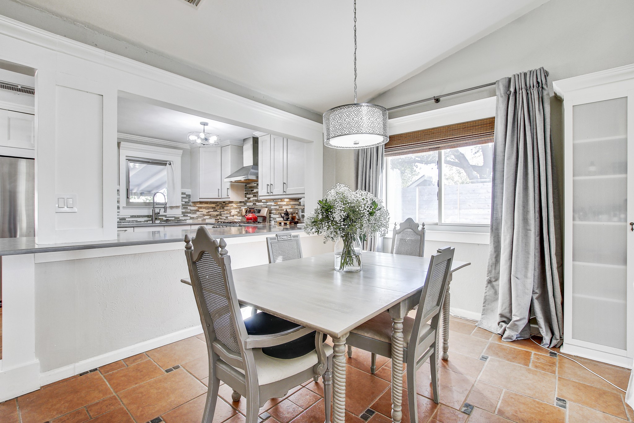 7741 Manassas Drive Austin, TX 78745 - Photo 10 of 39 Dining area with lofted ceiling, a chandelier, and stone tile flooring