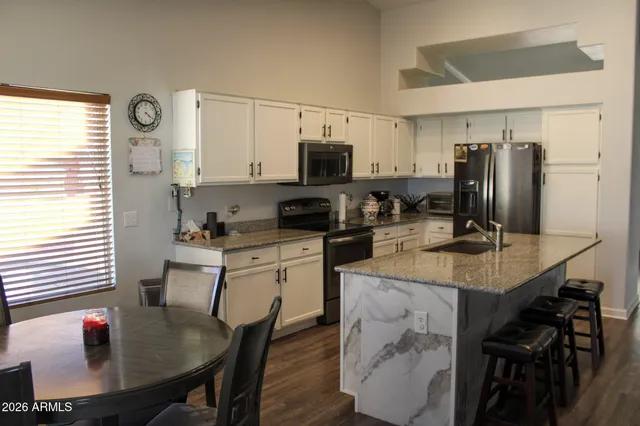 a kitchen with stainless steel appliances granite countertop a stove a sink a dining table and chairs