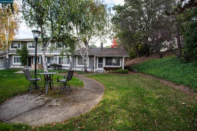 a view of a house with a yard chairs and table in patio