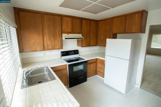 a kitchen with granite countertop wooden cabinets and white appliances