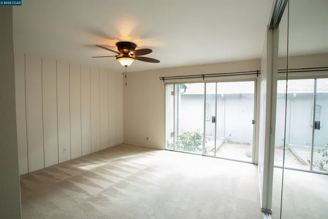 a view of a room with a ceiling fan and window