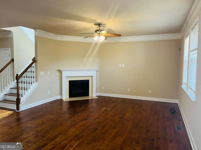 a view of an empty room with wooden floor fireplace and a window