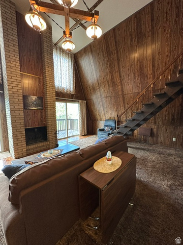 1085 West Elk Road Helper, UT 84526 - Photo 19 of 40 Vaulted ceiling living area featuring a brick fireplace, wood paneling, a large sliding glass door, and an open staircase with a wooden handrail