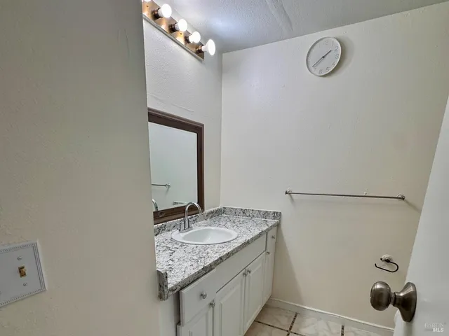 a bathroom with a granite countertop sink and a mirror