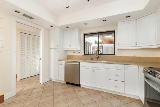 a kitchen with white cabinets and sink