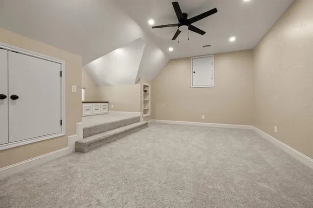an empty room with staircase ceiling fan and windows