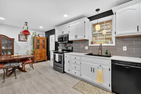 a kitchen with granite countertop a sink cabinets stainless steel appliances and a window
