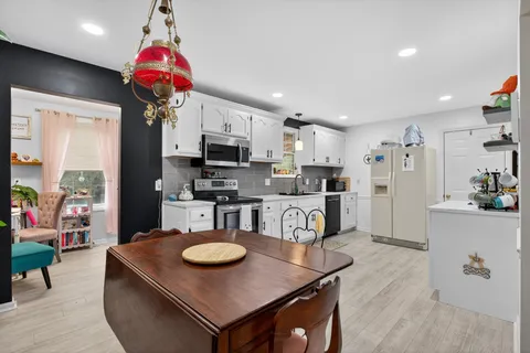 a kitchen with stainless steel appliances granite countertop a sink a stove a refrigerator cabinets and living room view