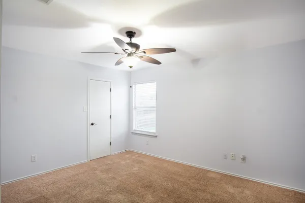 an empty room with a window and a fan