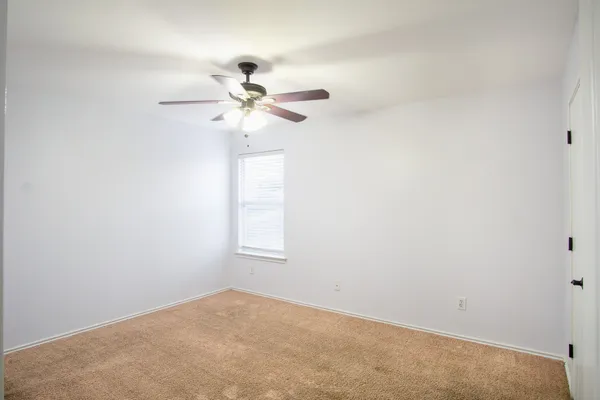 an empty room with a window and a fan