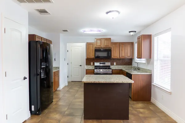 a kitchen with granite countertop a refrigerator stove and sink