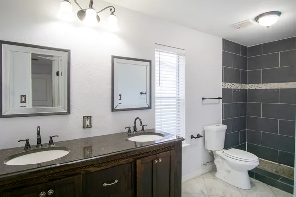 a bathroom with a granite countertop sink a toilet and a mirror