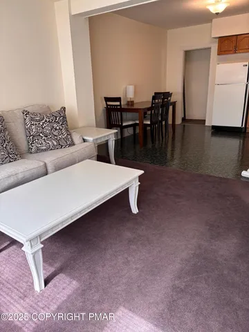 a living room with furniture and a dining table with kitchen view