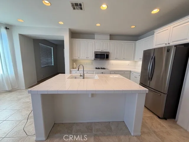 a kitchen with kitchen island a sink stainless steel appliances and refrigerator