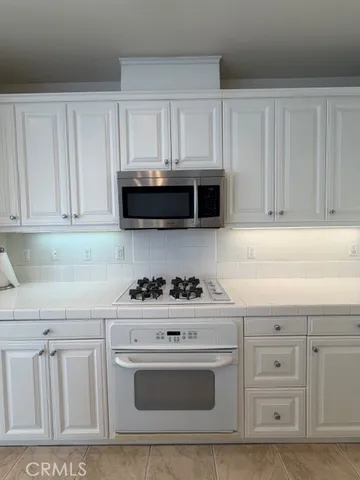 a kitchen with white cabinets and black appliances