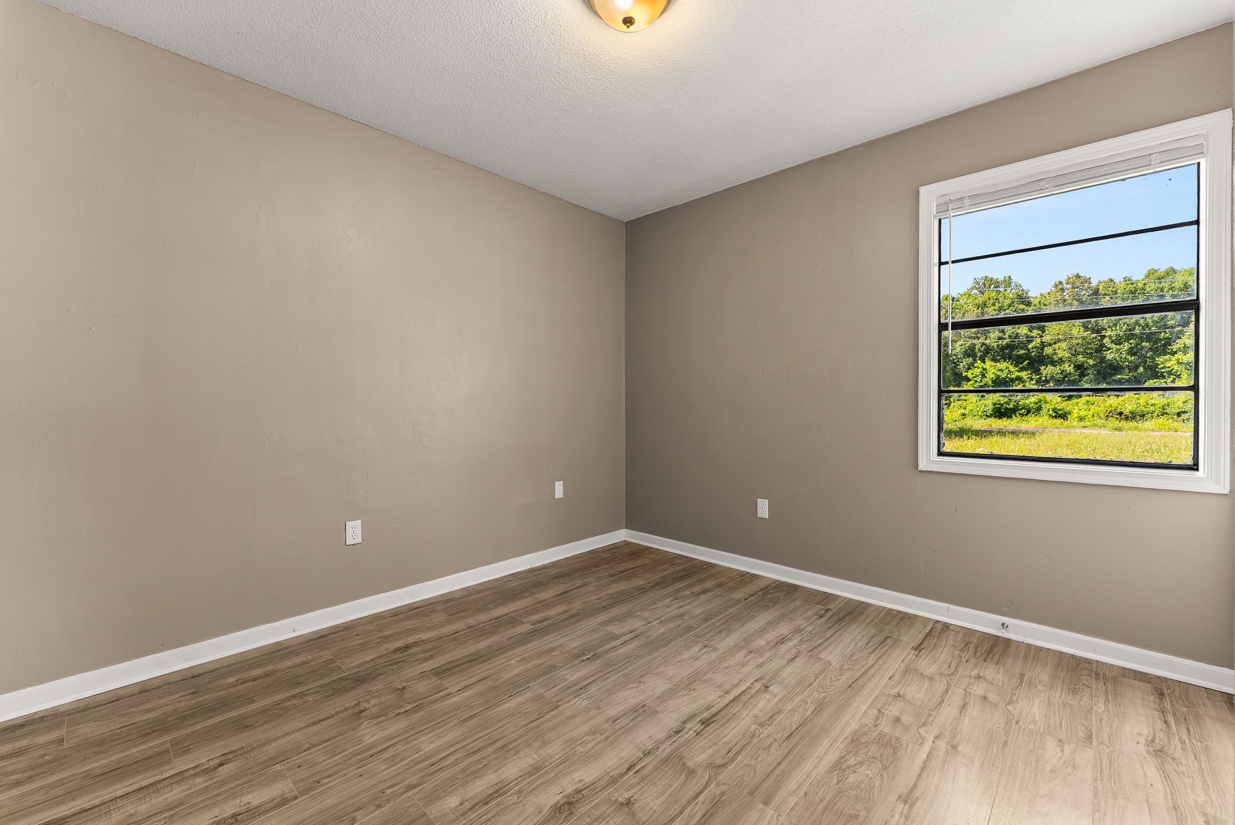 3759 McCain Road Memphis, TN 38109 - Photo 21 of 30 a view of an empty room with wooden floor and a window