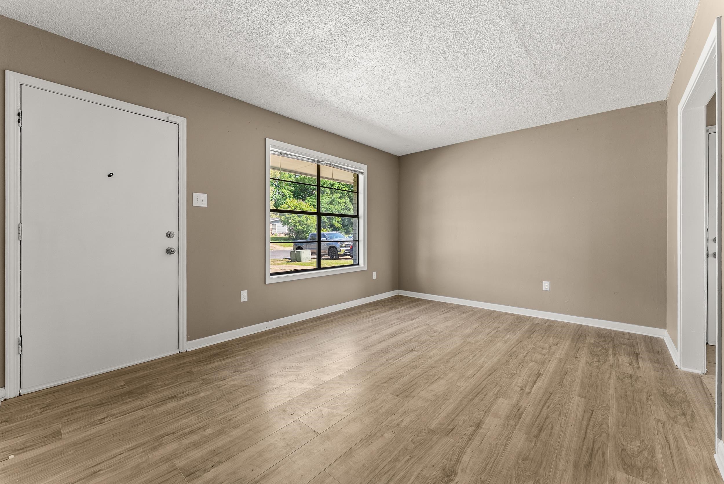 3759 McCain Road Memphis, TN 38109 - Photo 8 of 30 an empty room with wooden floor and windows