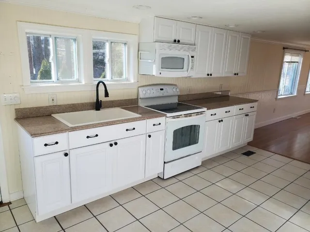 a kitchen with granite countertop white cabinets and white appliances