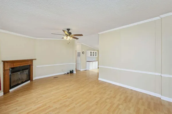 a view of an empty room with a fireplace and a ceiling fan