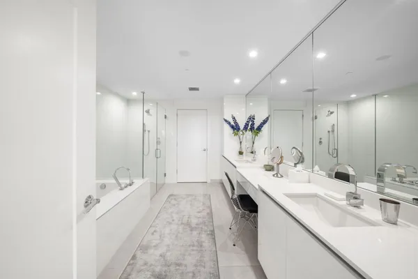 a large white kitchen with a double vanity sink and mirror