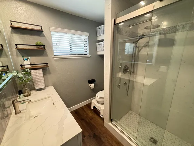 a bathroom with a granite countertop sink a mirror and a shower
