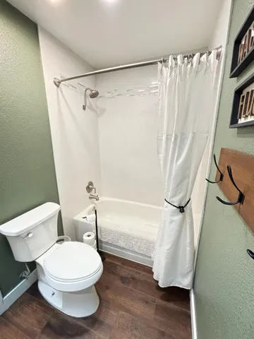 a white toilet sitting next to a bath tub and a shower