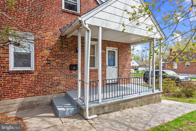 a view of a brick house with a small yard and wooden fence