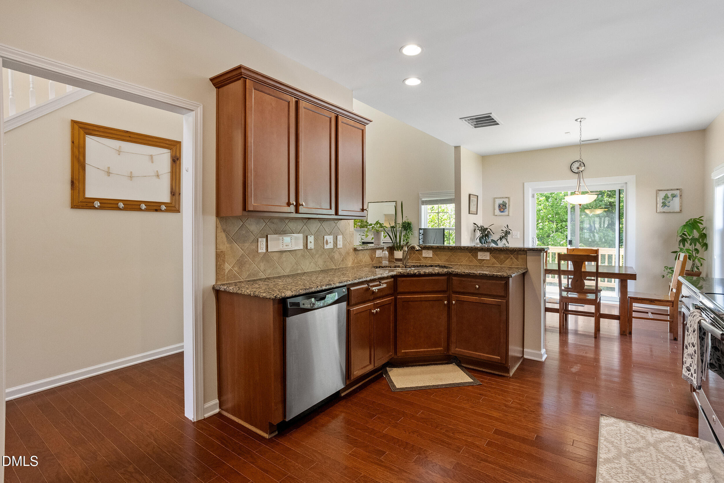 235 Strolling Way Durham, NC 27707 - Photo 12 of 32 a kitchen with granite countertop a stove top oven a sink dishwasher a dining table and chairs with wooden floor