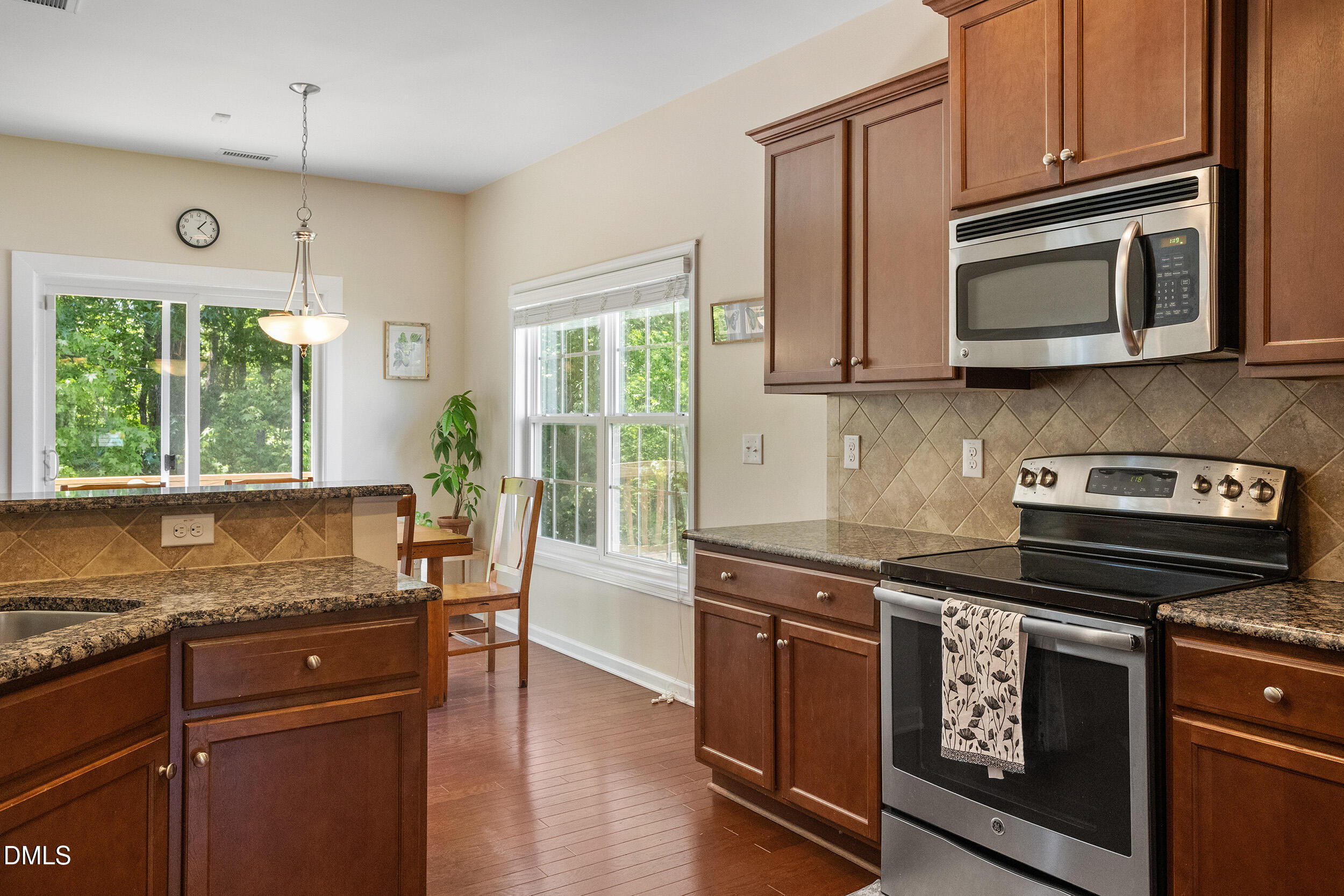 235 Strolling Way Durham, NC 27707 - Photo 13 of 32 a kitchen with granite countertop wooden cabinets stainless steel appliances and a large window