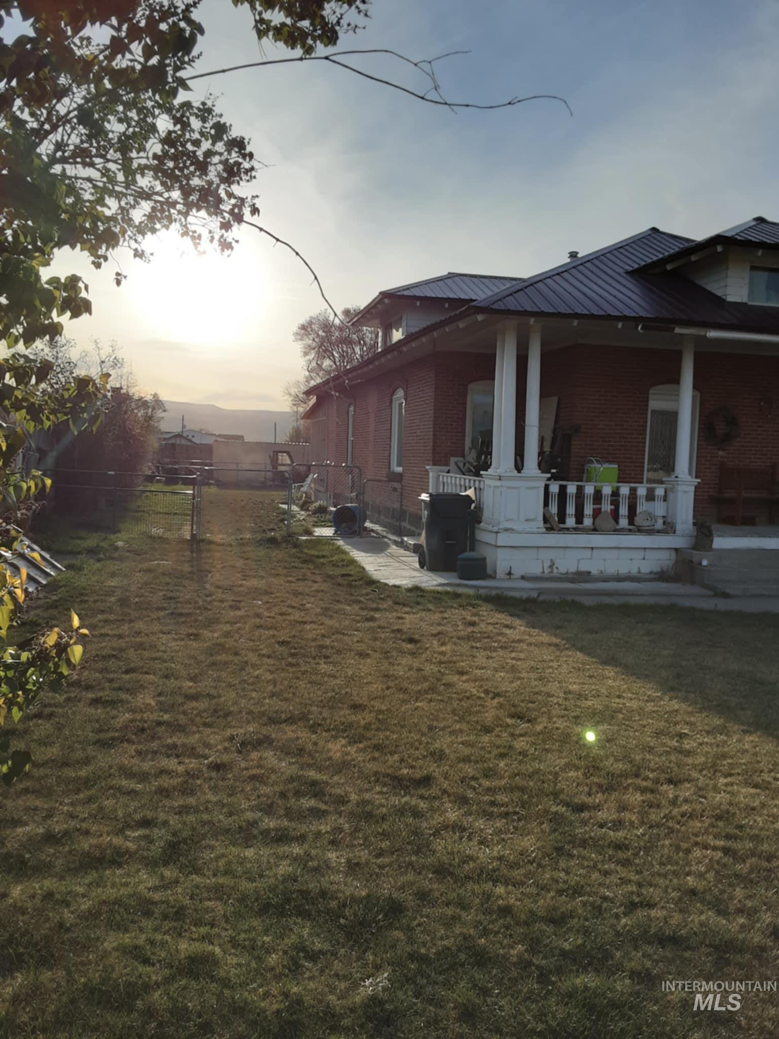 145 North Lincoln Avenue Oakley, ID 83346 - Photo 4 of 48 Property exterior at dusk with a patio, brick siding, and a metal roof