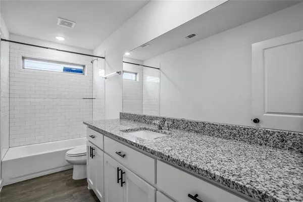 a bathroom with a granite countertop sink a toilet and shower