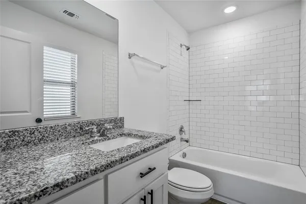 a bathroom with a granite countertop toilet a sink and a bathtub
