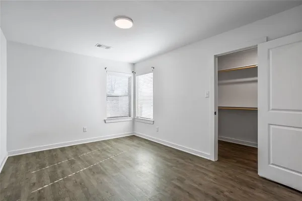 a view of an empty room with wooden floor & closet