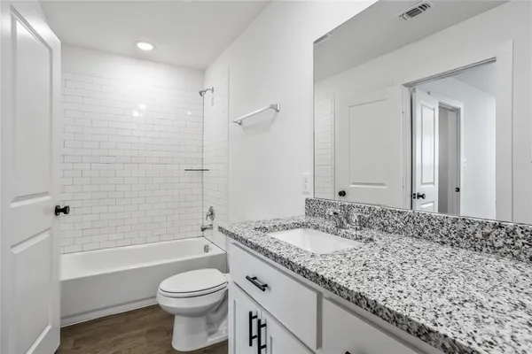 a bathroom with a granite countertop sink toilet and shower
