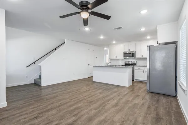 a large kitchen with stainless steel appliances a refrigerator and a stove top oven