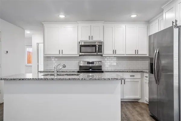 a kitchen with stainless steel appliances granite countertop a stove a sink and a refrigerator