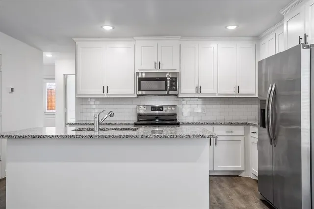 a kitchen with stainless steel appliances granite countertop a stove a sink and a refrigerator