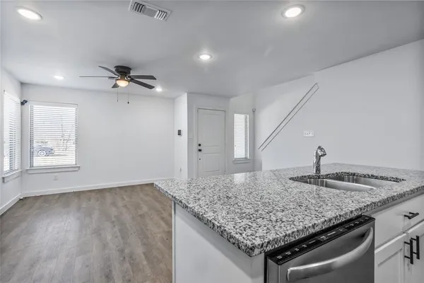 a view of kitchen island a sink wooden floor and chandelier