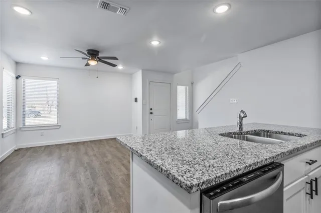 a view of kitchen island a sink wooden floor and chandelier