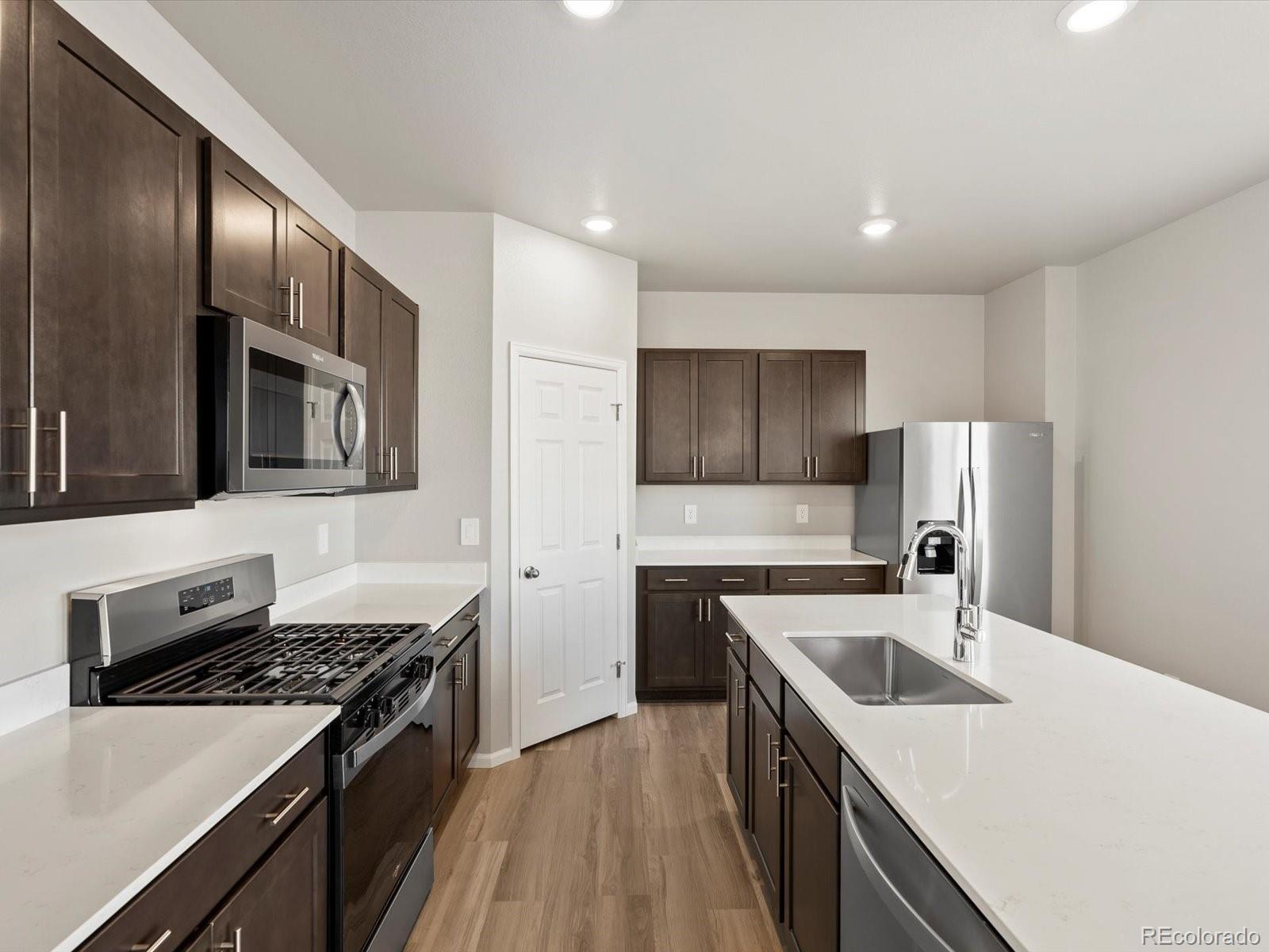 4673 Rabbitbrush Street Johnstown, CO 80534 - Photo 11 of 31 a kitchen with stainless steel appliances granite countertop a sink stove and refrigerator